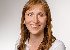 Christin Beyermann Porträt einer lächelnden Frau mit langen, braunen Haaren, die einen weißen Hemdkragen trägt. Der Hintergrund ist hell und neutral. Ihr Gesichtsausdruck ist freundlich und einladend.