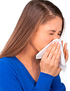 Junge Frau niest in ein Taschentuch, hält es vor Nase und Mund; blauer Pullover.